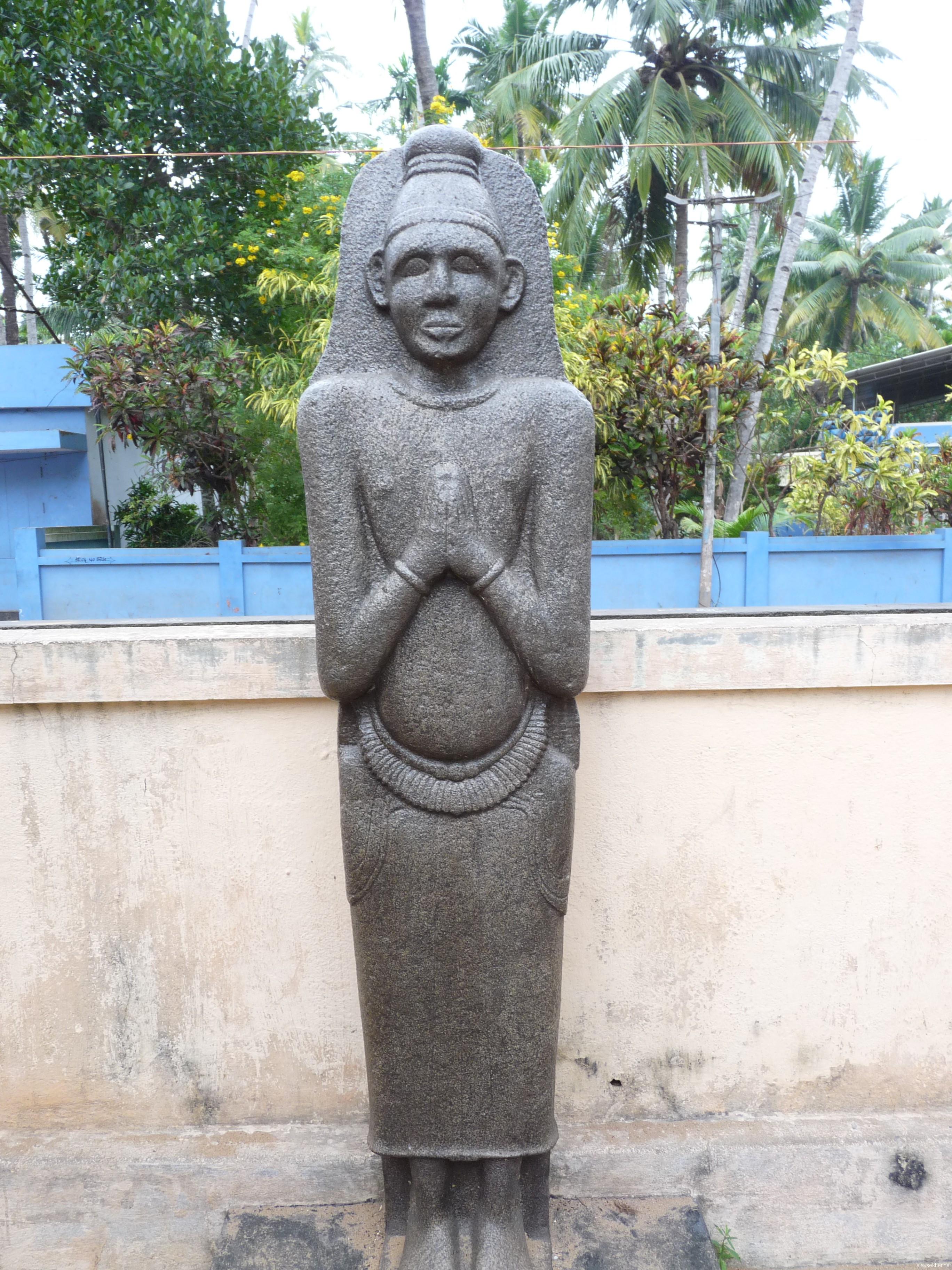 A granite idol recovered from a pond at the birth place of poet Kumaran Asan at Kayikara.  It is seen as Buddha by the local people.  Can be identified as a Siddha idol belonging to the late Vajrayana or Tantric Buddhist stage in Kerala history, the transitional period from Buddhism to Brahmanism in Kerala history.  Siddha is associated with Vajrayana while Arhat is associated with early Teravada or Hinayana and Boddhisatva is associated with Mahayana.  C V Kunhiraman has observed that Ezhava people traditionally worshiped the Chithan and Arathan.  Chithan is Sidhan and Arathan is Arhatan.  Boddhisatva has become Chathan.  It is also associated with Sastha another synonym for the buddha.  Idol now installed at Asan Memorial, Kayikara.